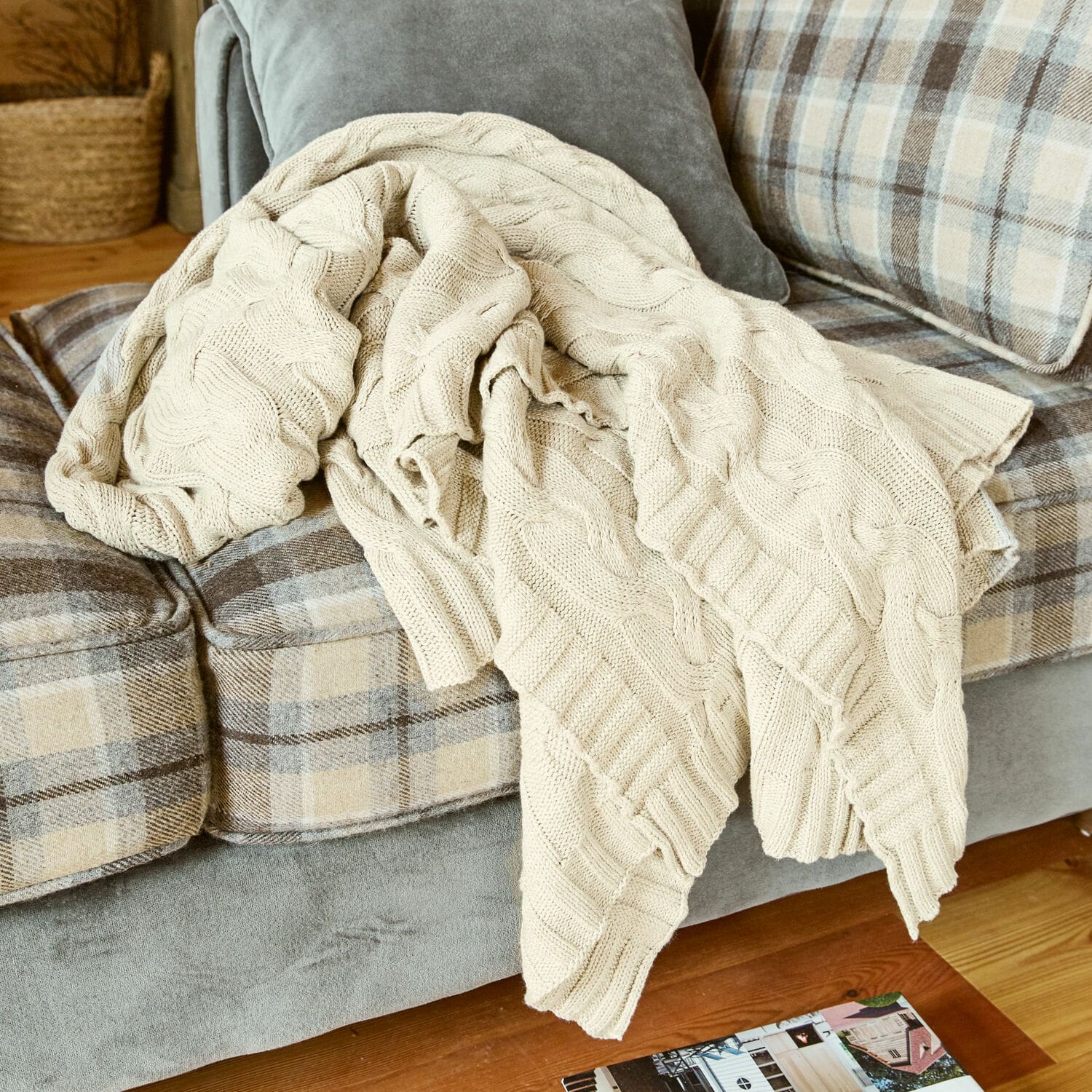 Plaid Arnhem Beige gestrickte Baumwolldecke auf grauem Sofa mit beigem Karomuster im Wohnzimmer