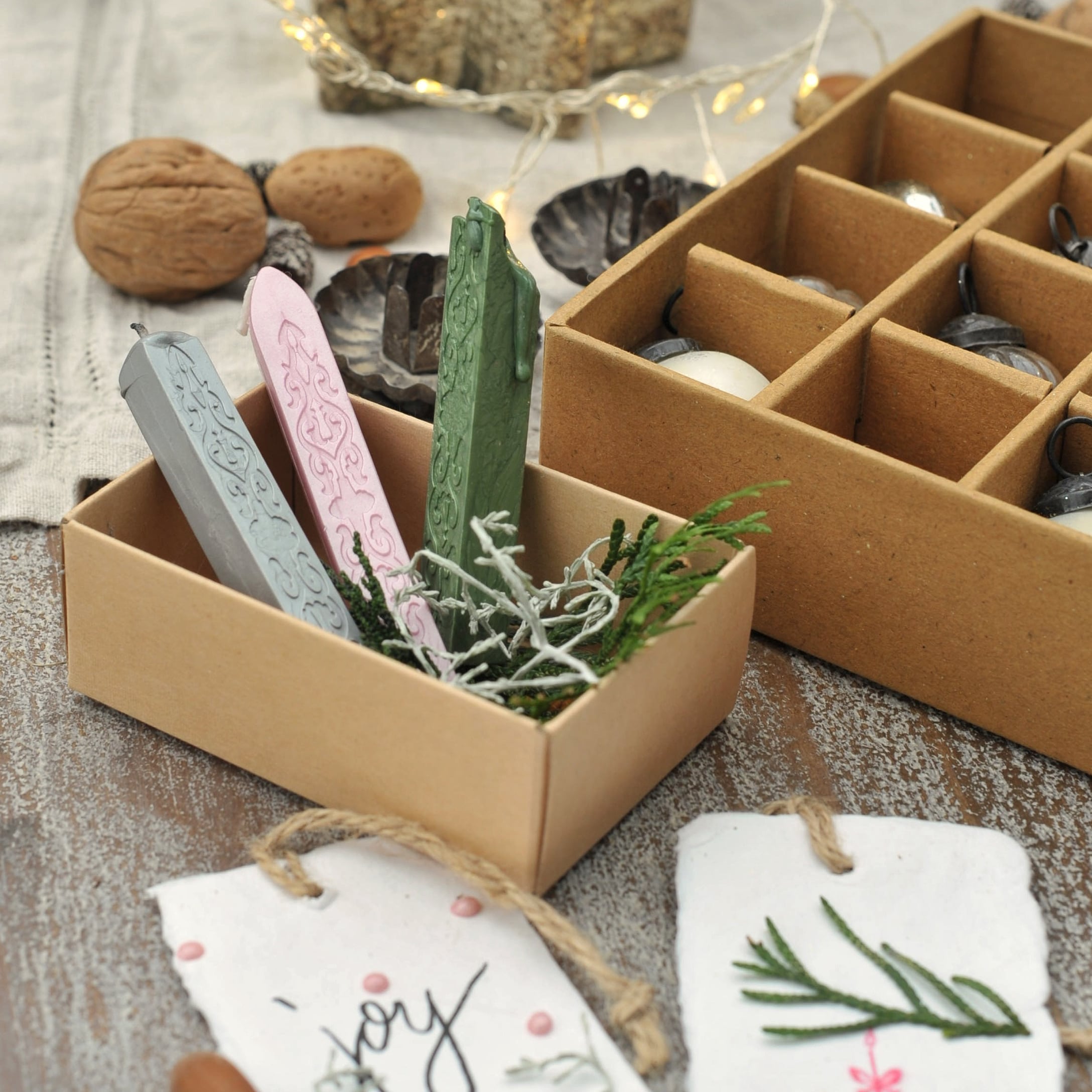 Drei bunte Siegellackstangen in einer Schachtel mit Naturdeko auf einem Holztisch für Geschenkverpackungen