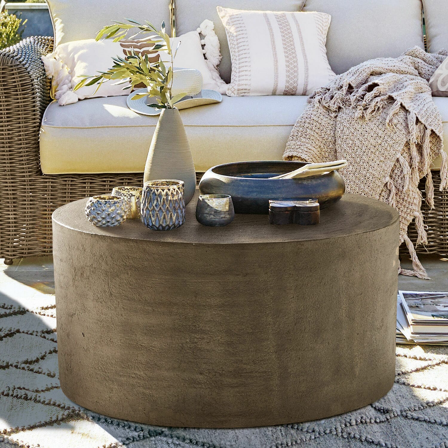 Couchtisch Lexy Runder Couchtisch aus grauem Beton auf der Terrasse mit Dekorationen und Rattansofa