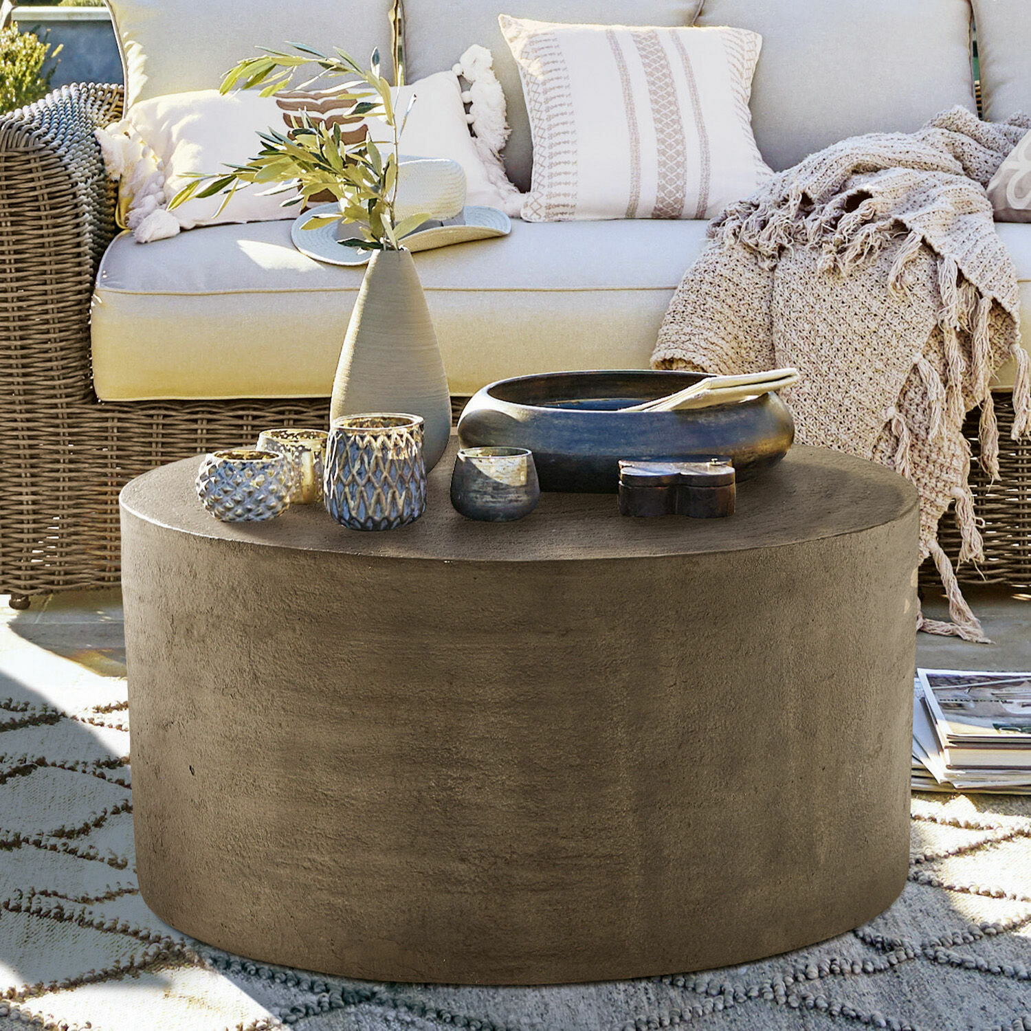 Couchtisch Lexy Runder Couchtisch aus grauem Beton auf der Terrasse mit Dekorationen und Rattansofa