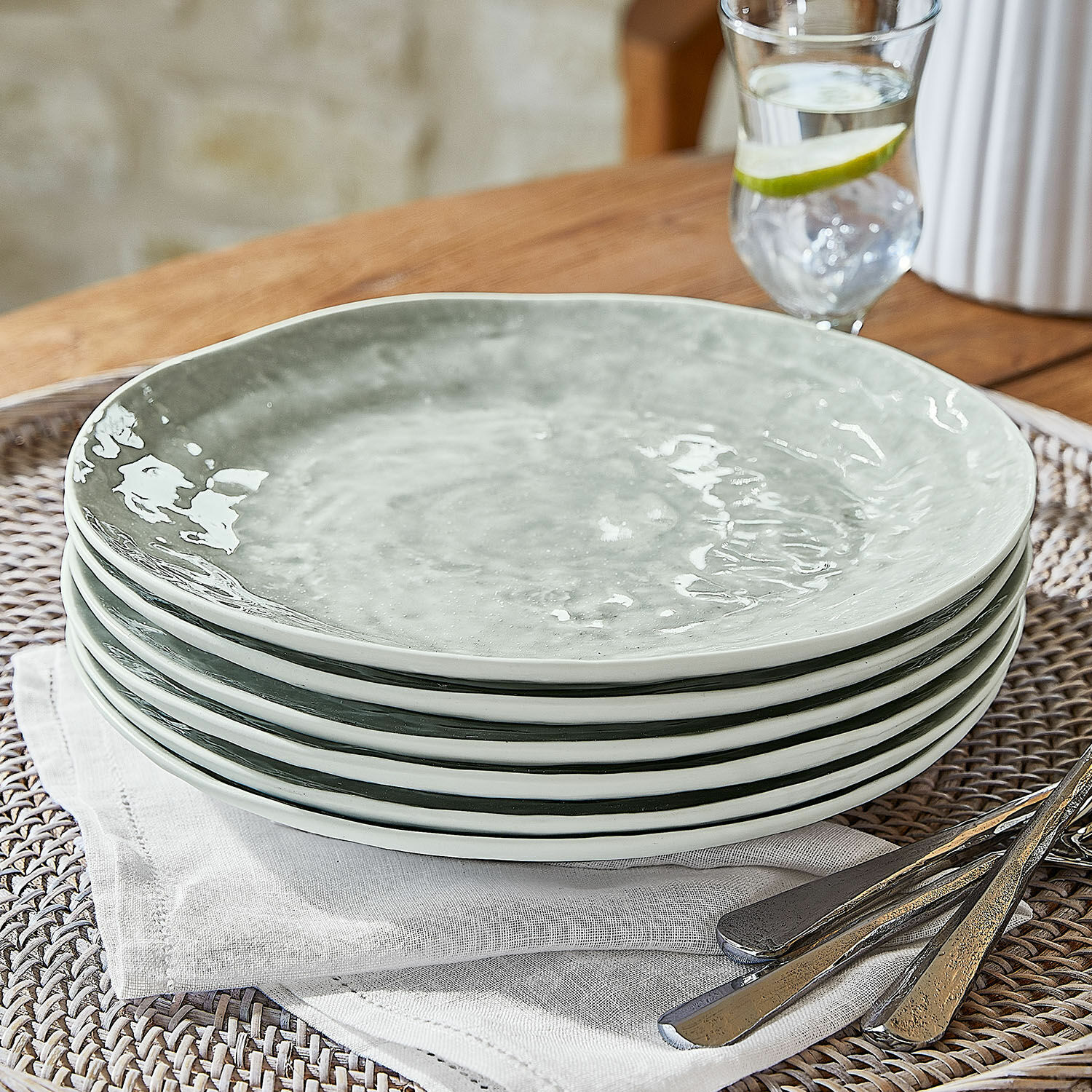 Sechser-Set grauer Keramikteller auf Leinenserviette mit Metallbesteck für den gedeckten Tisch