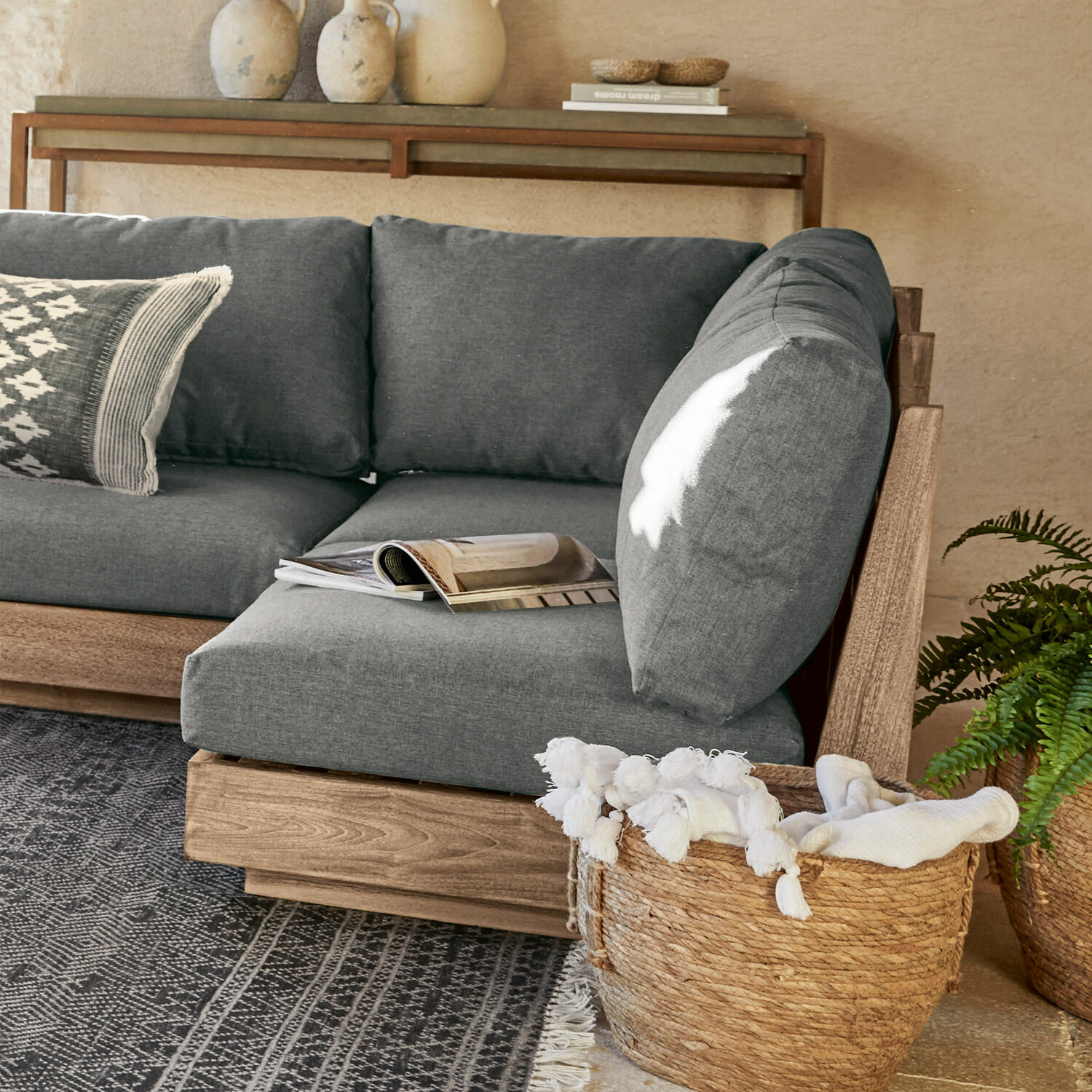Sofaelement Courtelevant Graues Sofa mit Holzrahmen und weichen Kissen in modernem Wohnzimmer mit Weidenkorb