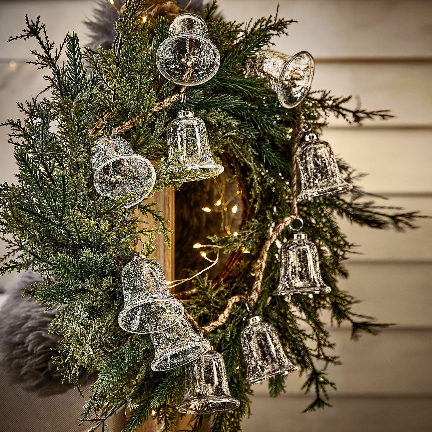 Weihnachtsgirlande mit grünen Zweigen und transparenten Glasglocken zur Wohnraumdekoration