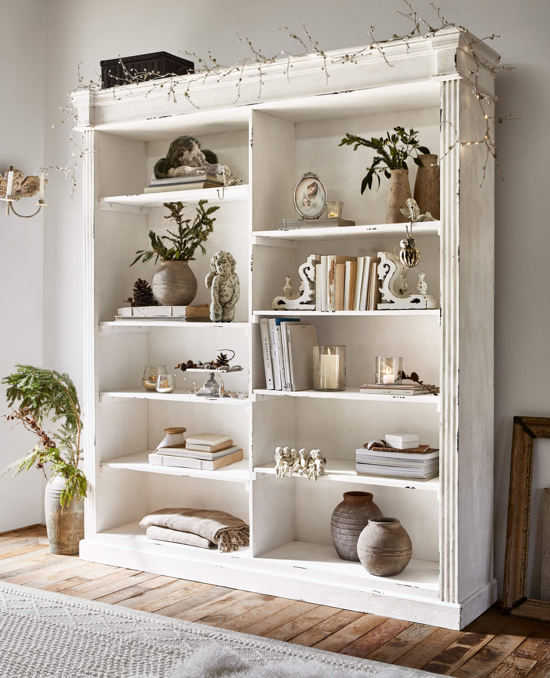 Weisses Holzregal mit Vintage-Dekorationen und Büchern auf hellem Holzboden