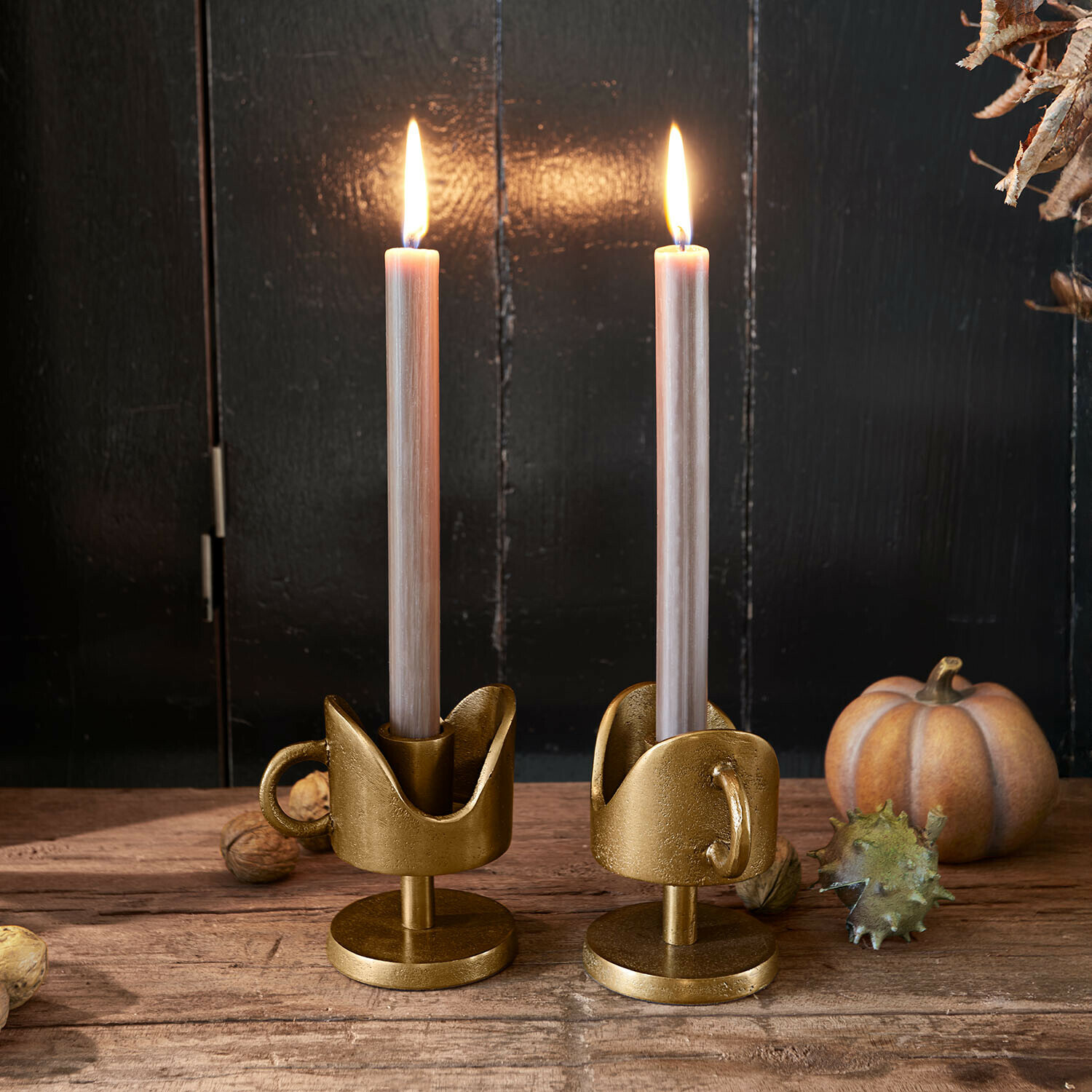 Kerzenhalter 2er Set Mirodella Paar goldene Metall-Kerzenhalter mit Griffen und beigen Kerzen auf Holztisch mit Herbstdekorationen