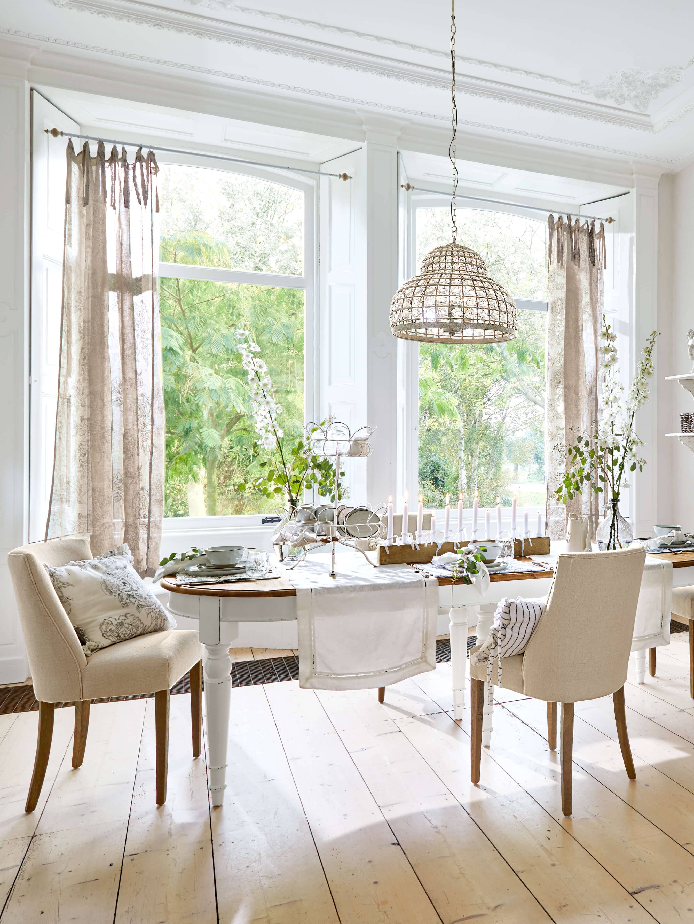 Esszimmer mit weissem Holztisch und beigen Stühlen, natürliches Licht und Dekorationen