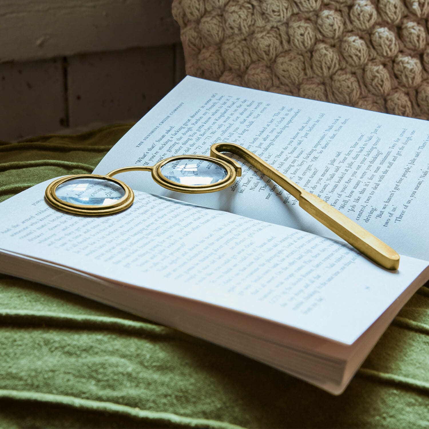 Lupe Robert Goldene Lesebrille mit runden Gläsern auf offenem Buch auf grünem Stoff