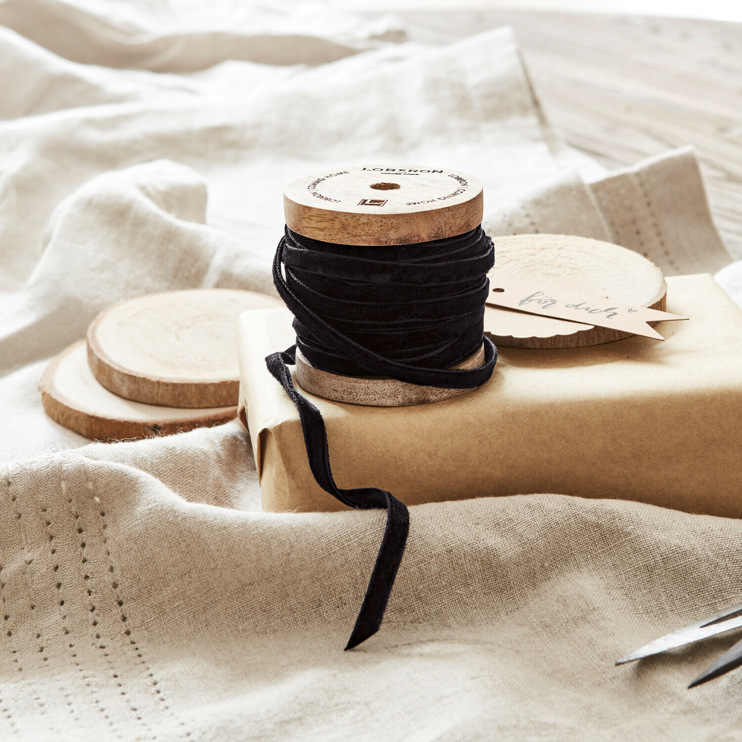Samtband Olessa Schwarzes Samtband auf Holzspule mit Naturpapier und Schere zum Geschenkverpacken