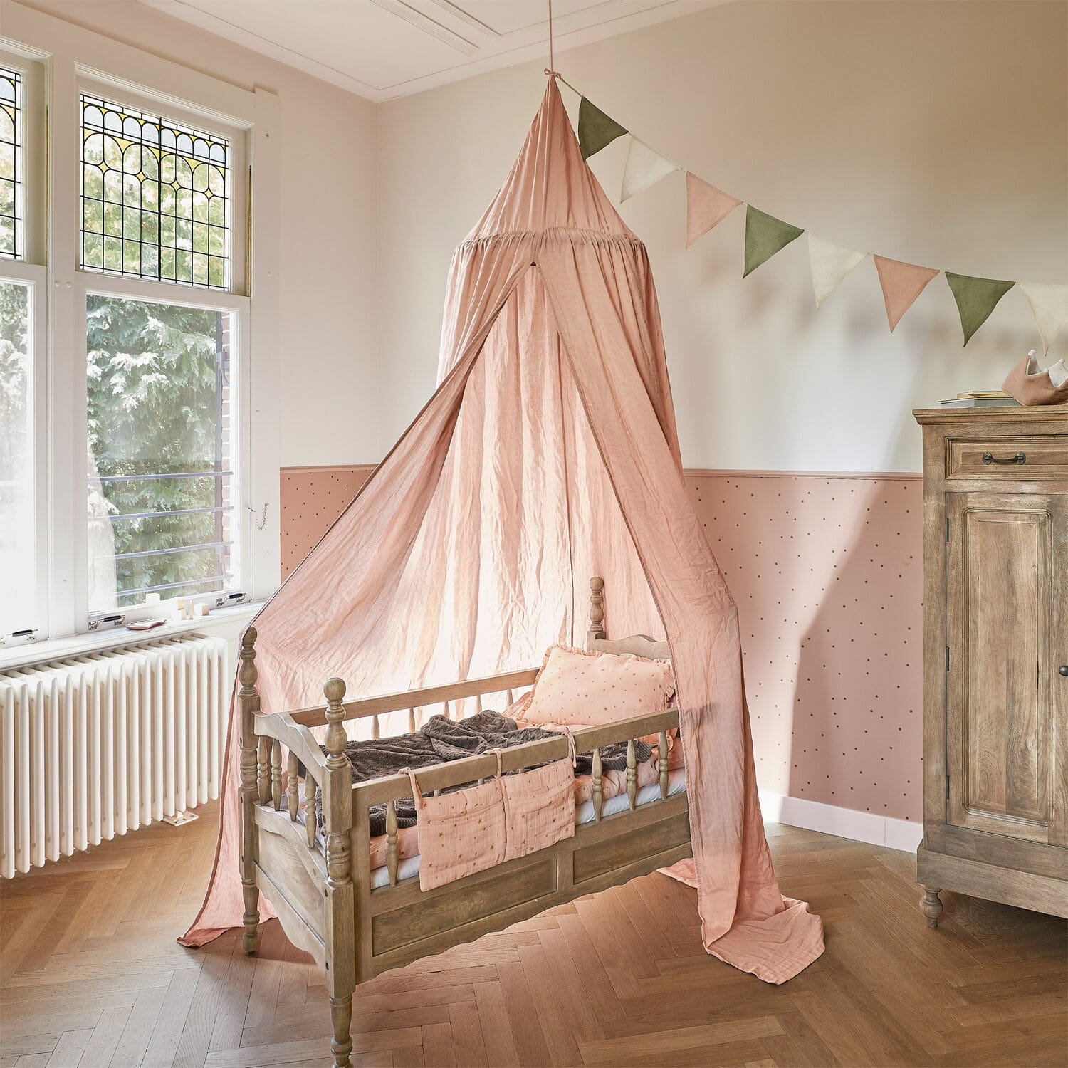 Betthimmel Lisonne Kinderbett aus Holz mit rosa Baldachin und dekorativen Kissen im hellen Kinderzimmer