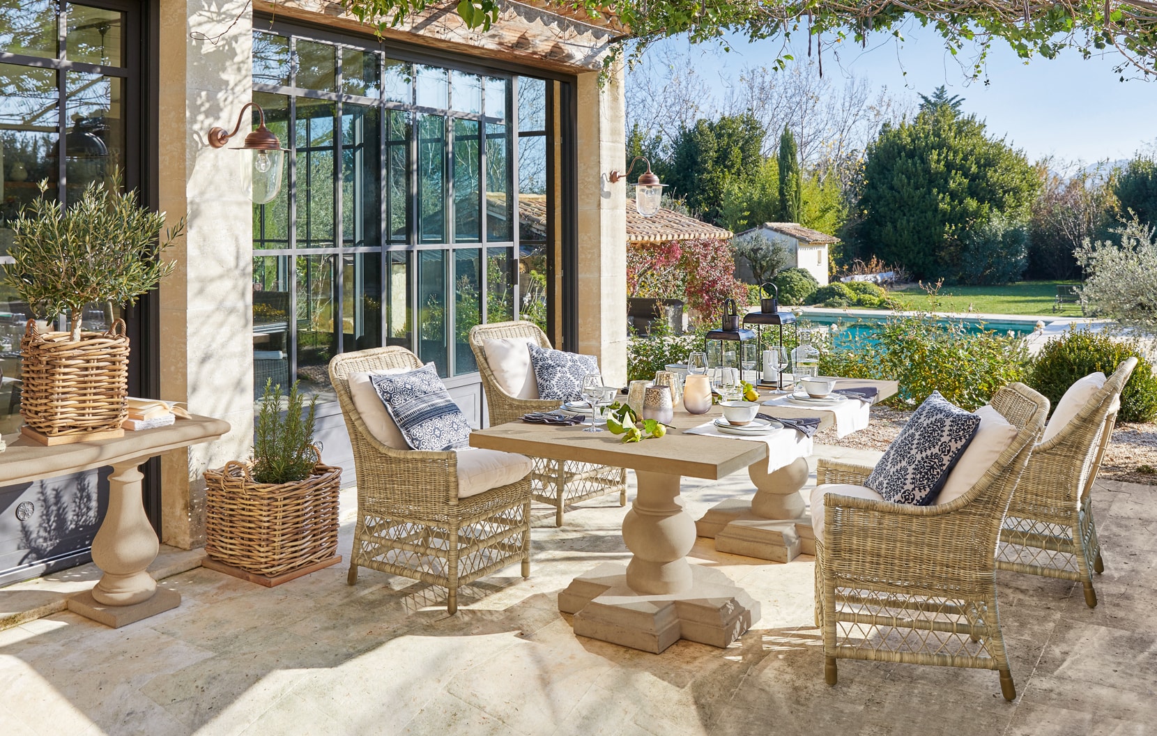 Gemütliche Terrasse mit Rattanmöbeln und Steintisch im mediterranen Stil mit Blick auf den Pool.