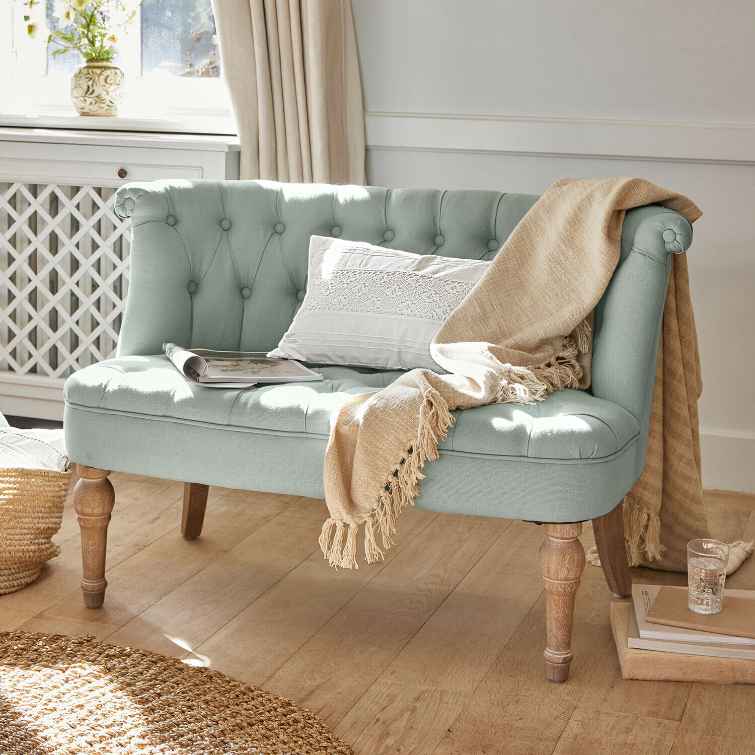 Mintgrünes, gepolstertes Sofa mit Holzbeinen, beiger Decke und weißem Kissen im Vintage-Stil