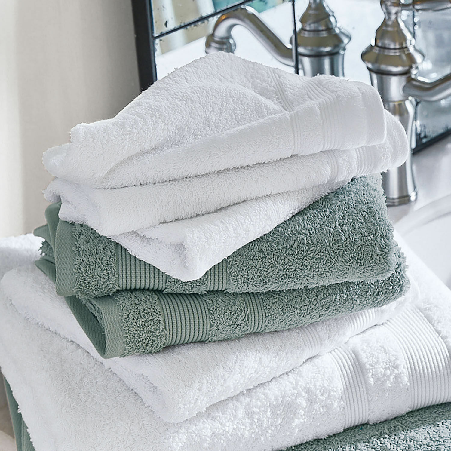 Handtuch 4er Set Bourogne Weiche Baumwollhandtücher in Weiss und Grün, im Badezimmer neben dem Wasserhahn gestapelt
