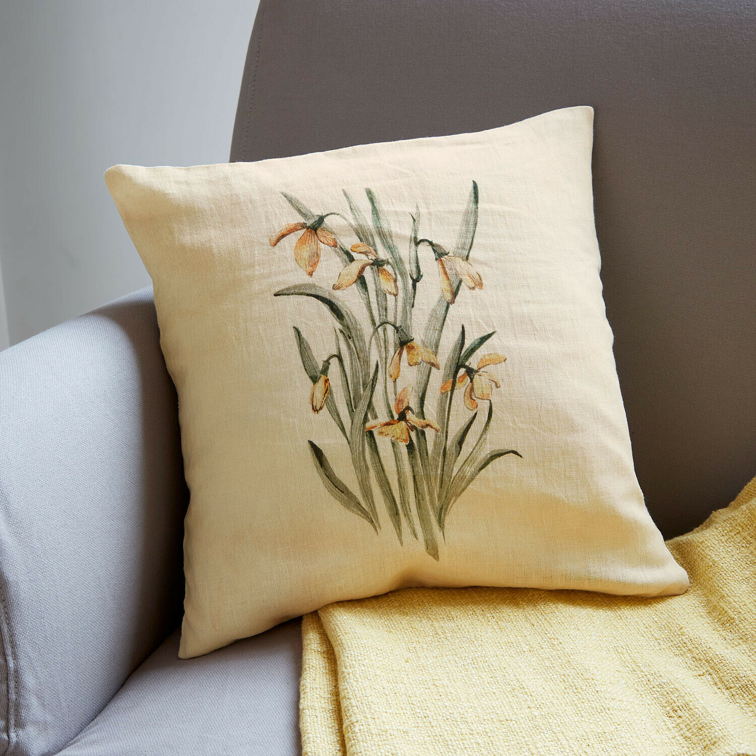 Kissenhülle Lozere Beiges Leinenkissen mit gelbem Blumenmuster auf grauem Sofa mit gelber Decke