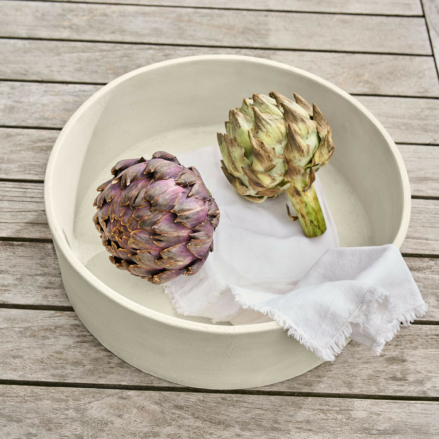 Schale Islene Runde cremefarbene Keramikschale mit zwei Artischocken und weissem Tuch auf Holztisch