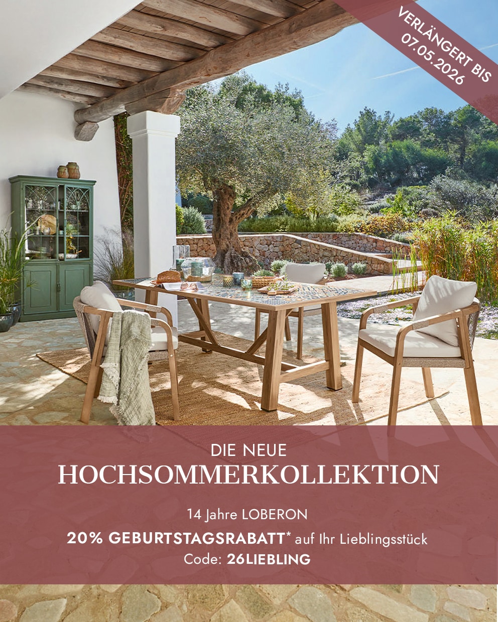 Gartenmöbel-Set mit Holztisch und Stühlen mit hellen Polstern auf Terrasse mit Gartenblick