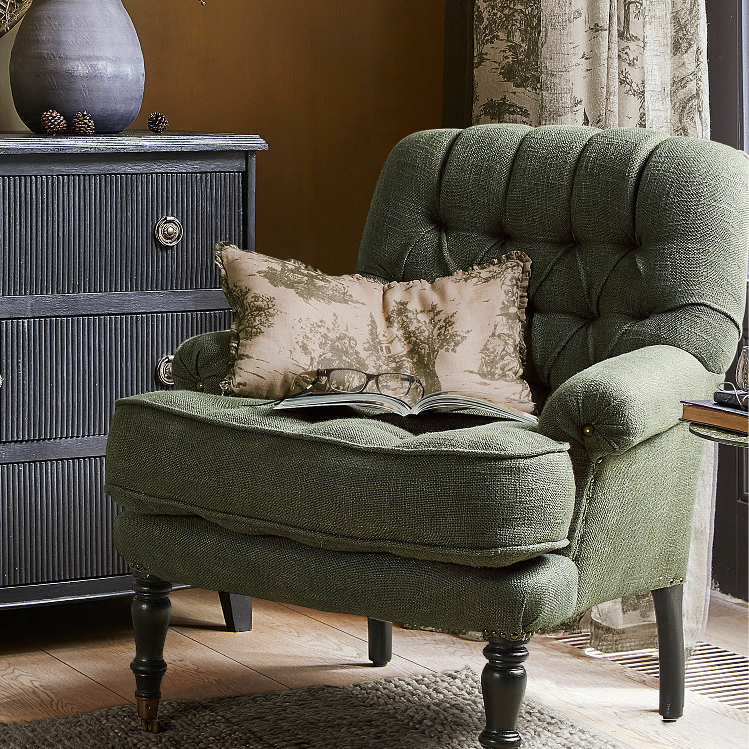 Grüner Polstersessel aus Stoff mit Kissen und Buch, stilvolles Wohnzimmermöbel
