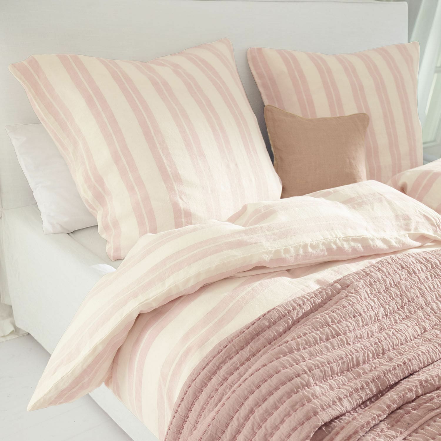 Bettwäsche Dordogne Bettwäsche aus Baumwolle in rosa-cremefarbenen Streifen mit weicher rosa Decke auf hellem Bett.