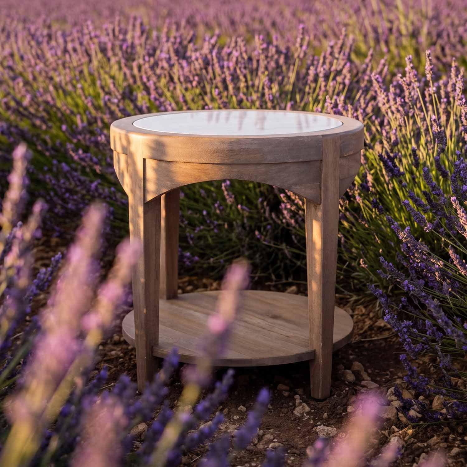 Runder Holztisch mit weisser Tischplatte, umgeben von violetten Lavendelpflanzen im Freien