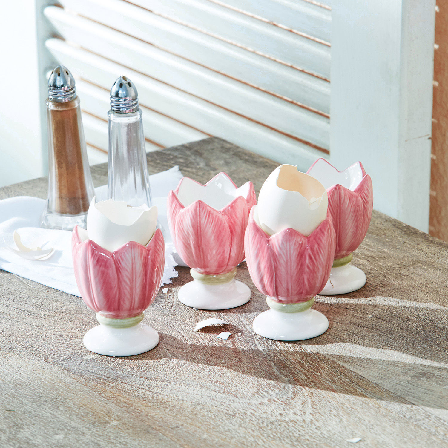 Eierbecher 4er Set Mireille Keramische rosa Eierbecher in Tulpenform auf Holztisch mit Salz- und Pfefferstreuer