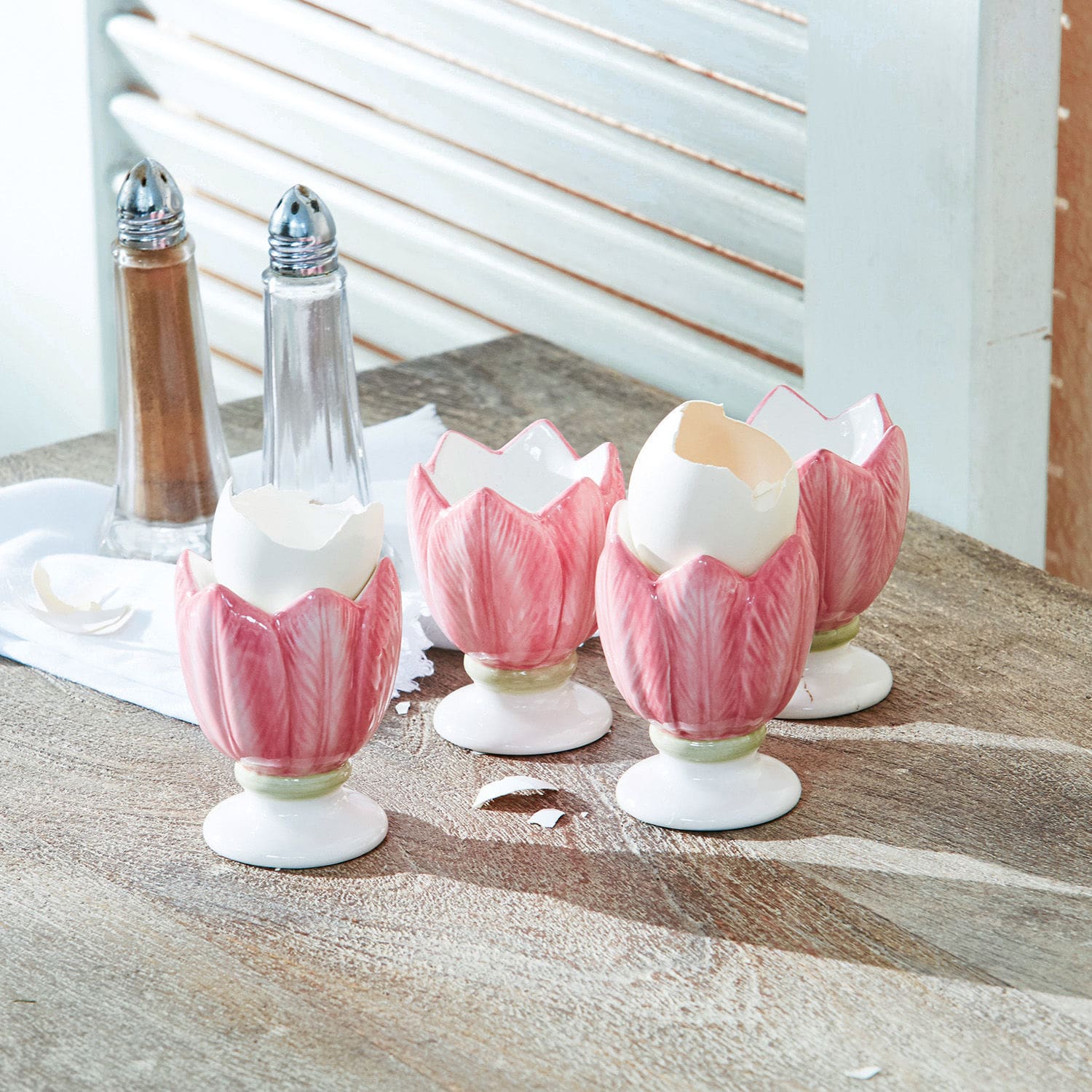 Eierbecher 4er Set Mireille Keramische rosa Eierbecher in Tulpenform auf Holztisch mit Salz- und Pfefferstreuer