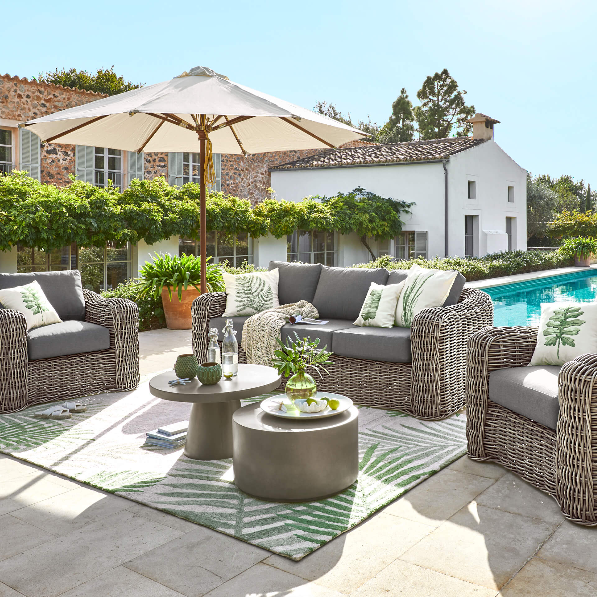 Gartenmöbelset aus grauem Technorattan mit Kissen und Sonnenschirm am Pool