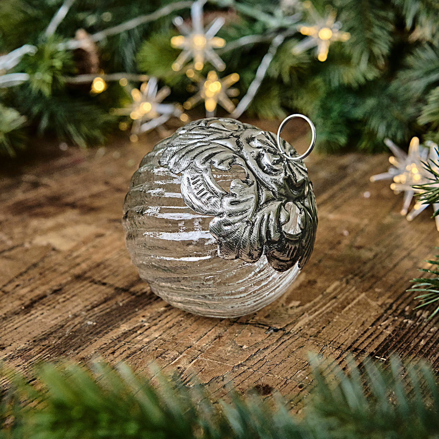 Weihnachtskugel Zoriline Glaskugel mit silberner Metallverzierung auf Holztisch mit grünen Tannenzweigen als Weihnachtsdekoration