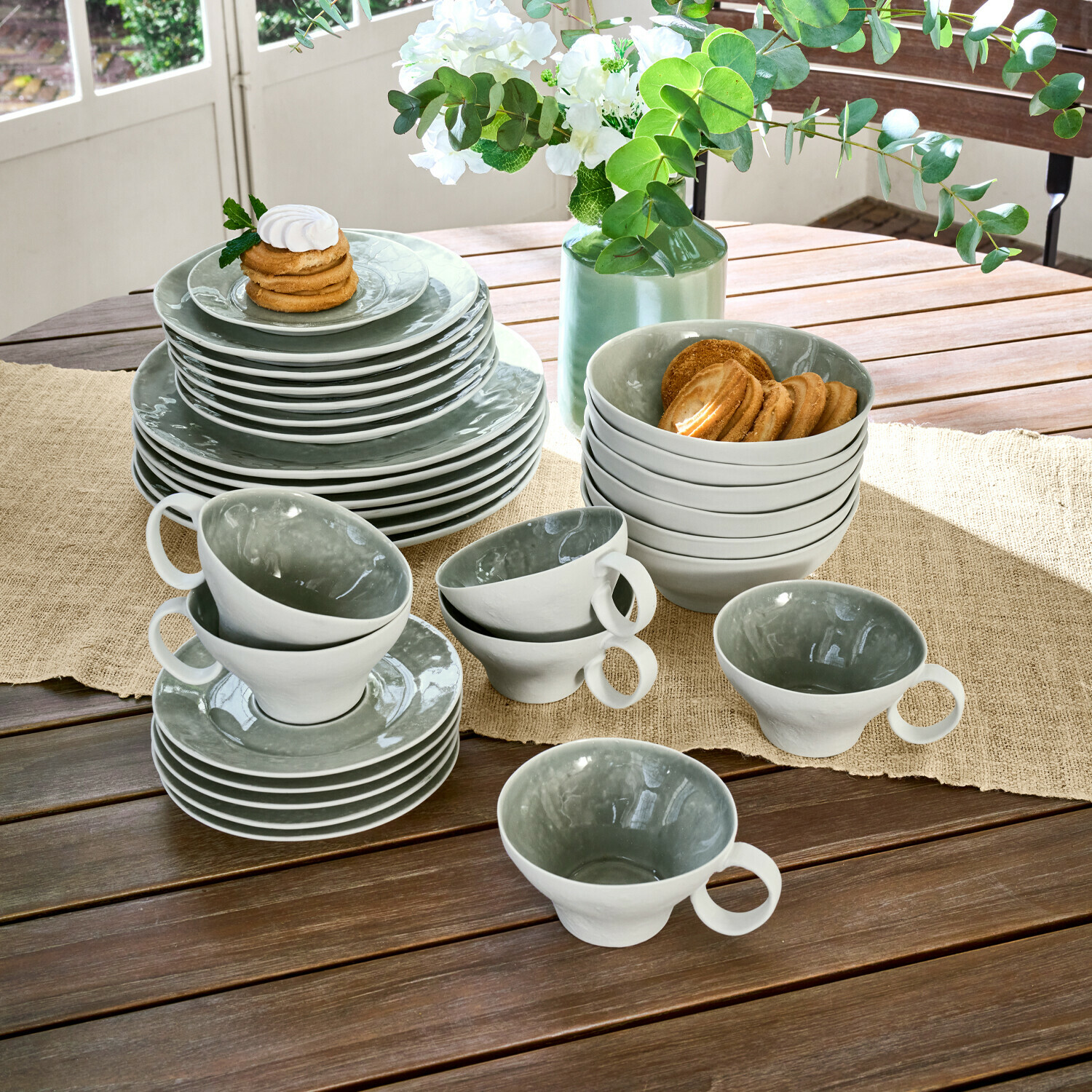 Geschirr 30er Set Braganza Keramikgeschirr-Set in Grau und Weiß auf Holztisch mit Keksen und Blumenarrangement