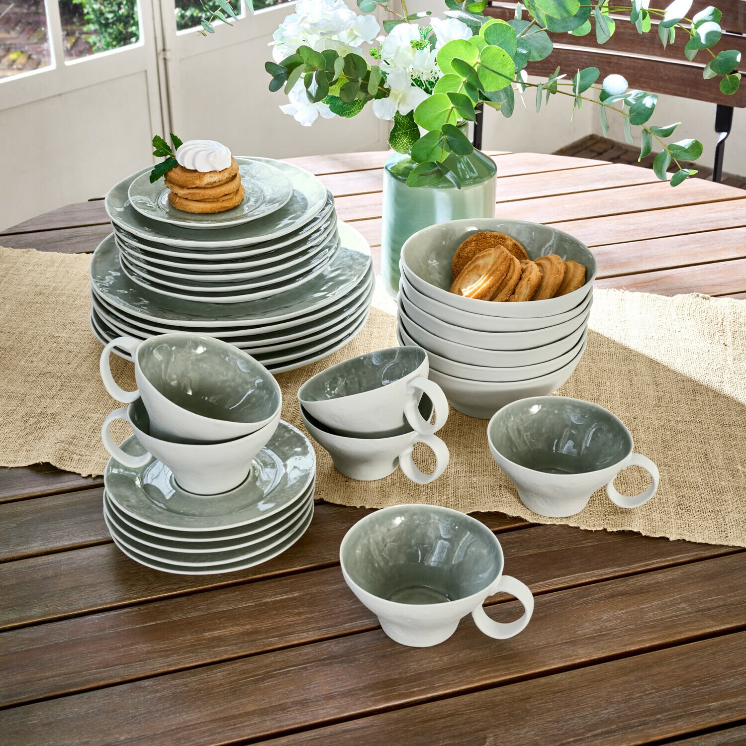 Geschirr 30er Set Braganza Keramikgeschirr-Set in Grau und Weiß auf Holztisch mit Keksen und Blumenarrangement
