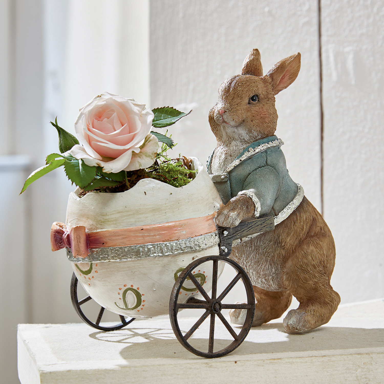 Hase Alençon Braune Hasenfigur aus Material schiebt weissen Wagen in Eiform mit rosa Rose