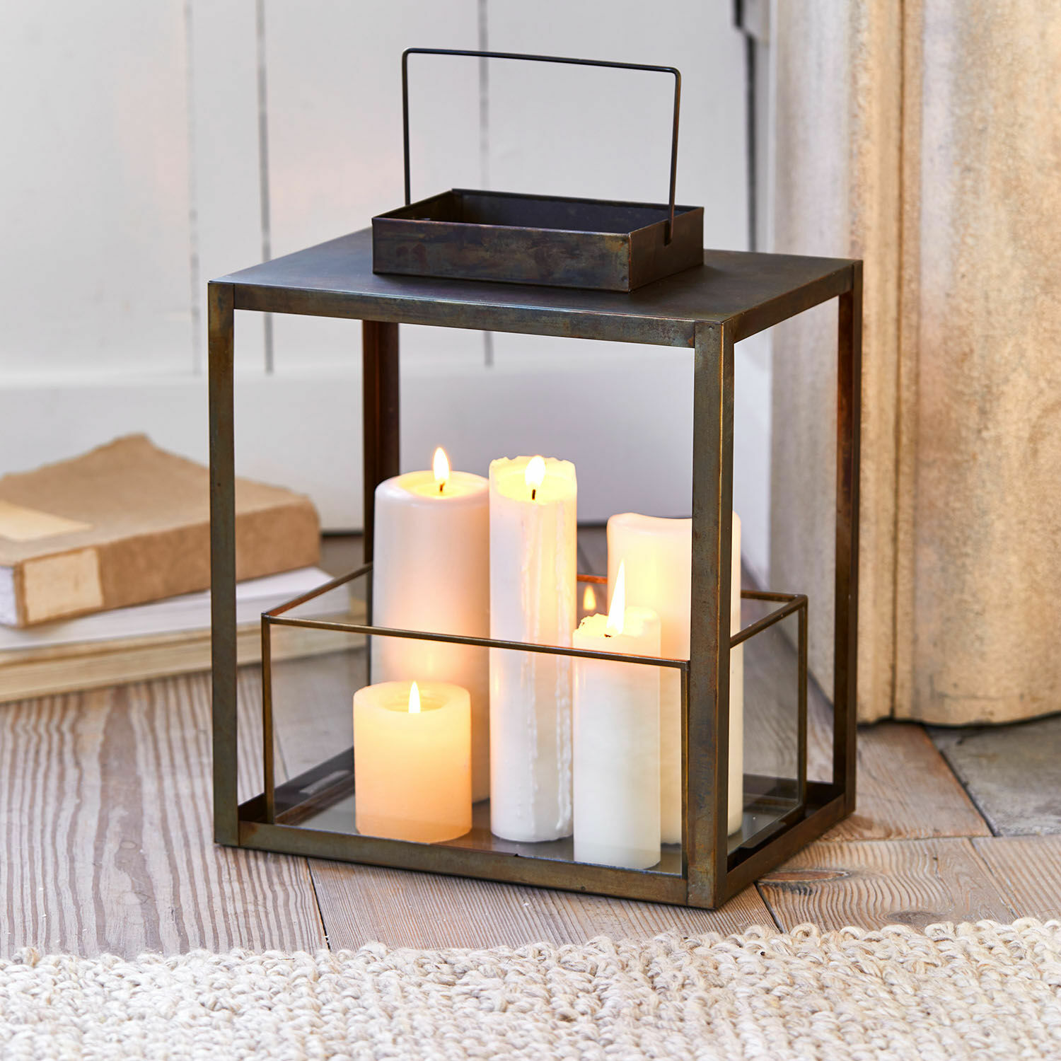Laterne Abbracciante Metalllaterne mit klarem Glas und weissen brennenden Kerzen auf Holzboden, Wohnaccessoire