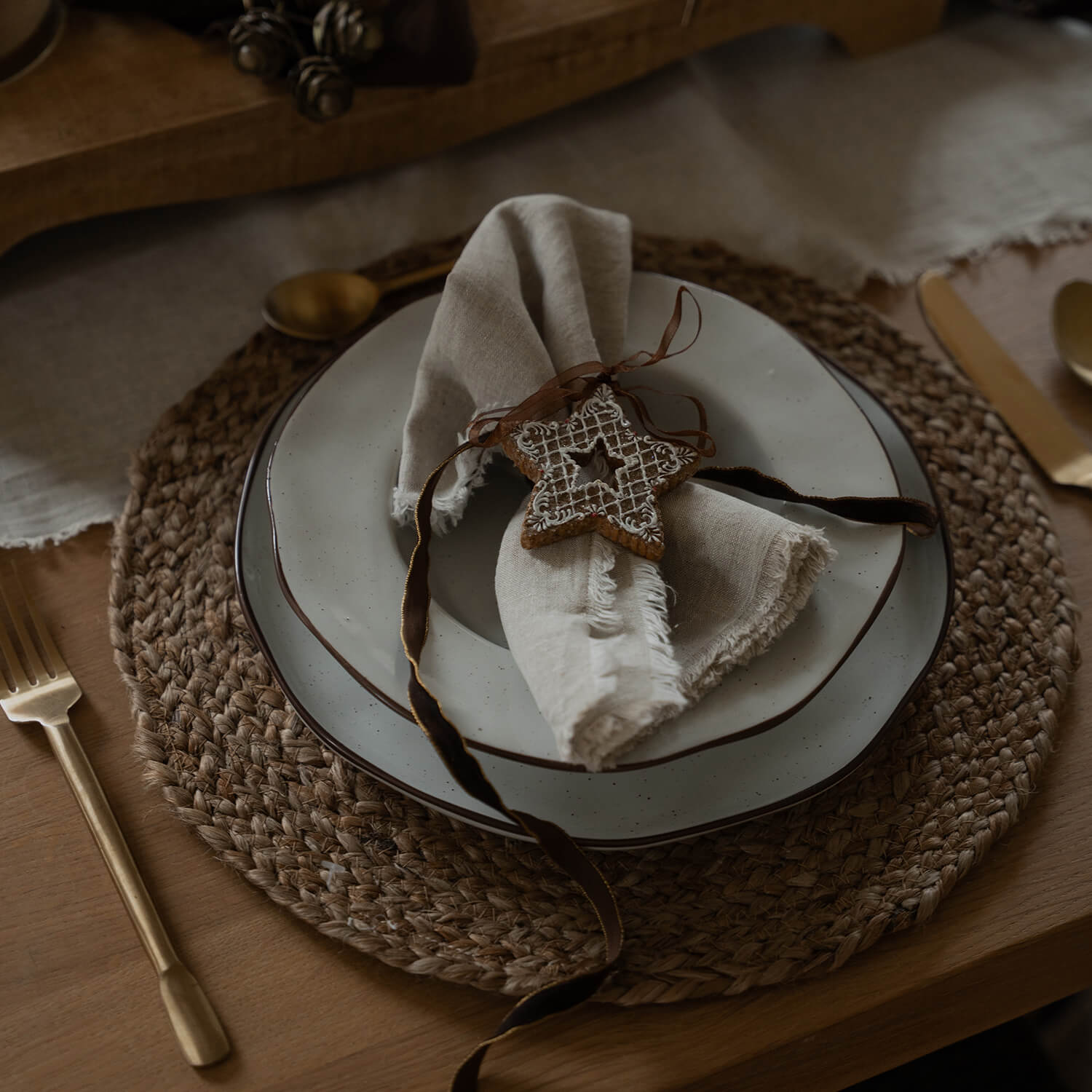 Rustikales Tischset mit Keramiktellern und Leinenserviette mit verziertem Lebkuchenstern