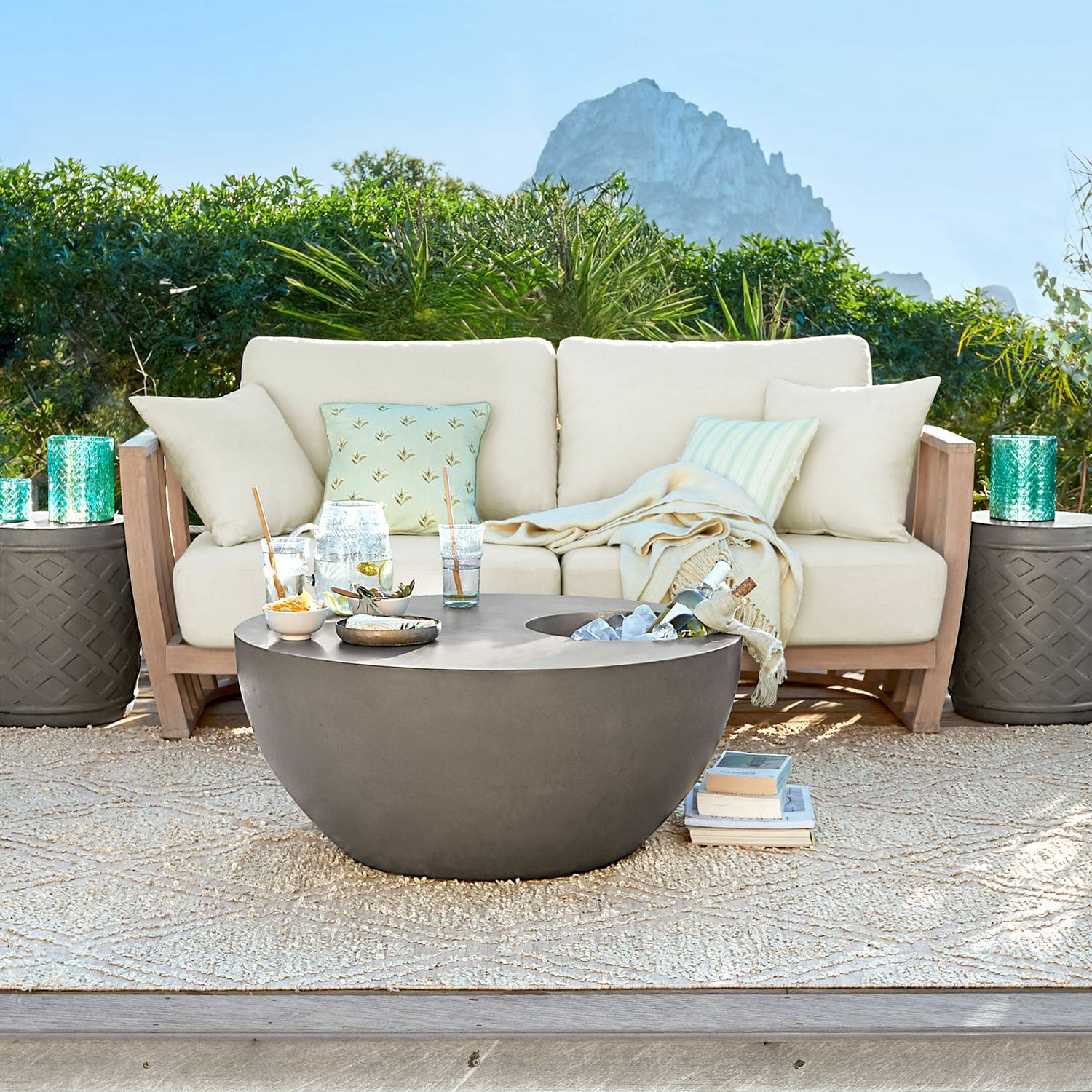 Sofa FSC®-100% Vézère Moderner runder Gartentisch aus grauem Beton auf der Terrasse mit beigem Sofa und Kissen
