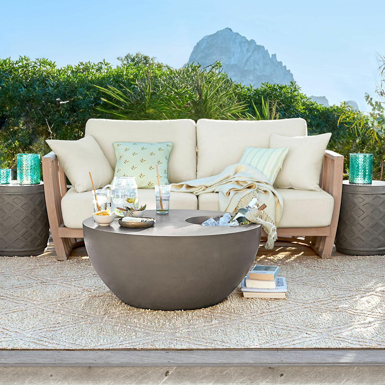 Sofa FSC®-100% Vézère Moderner runder Gartentisch aus grauem Beton auf der Terrasse mit beigem Sofa und Kissen
