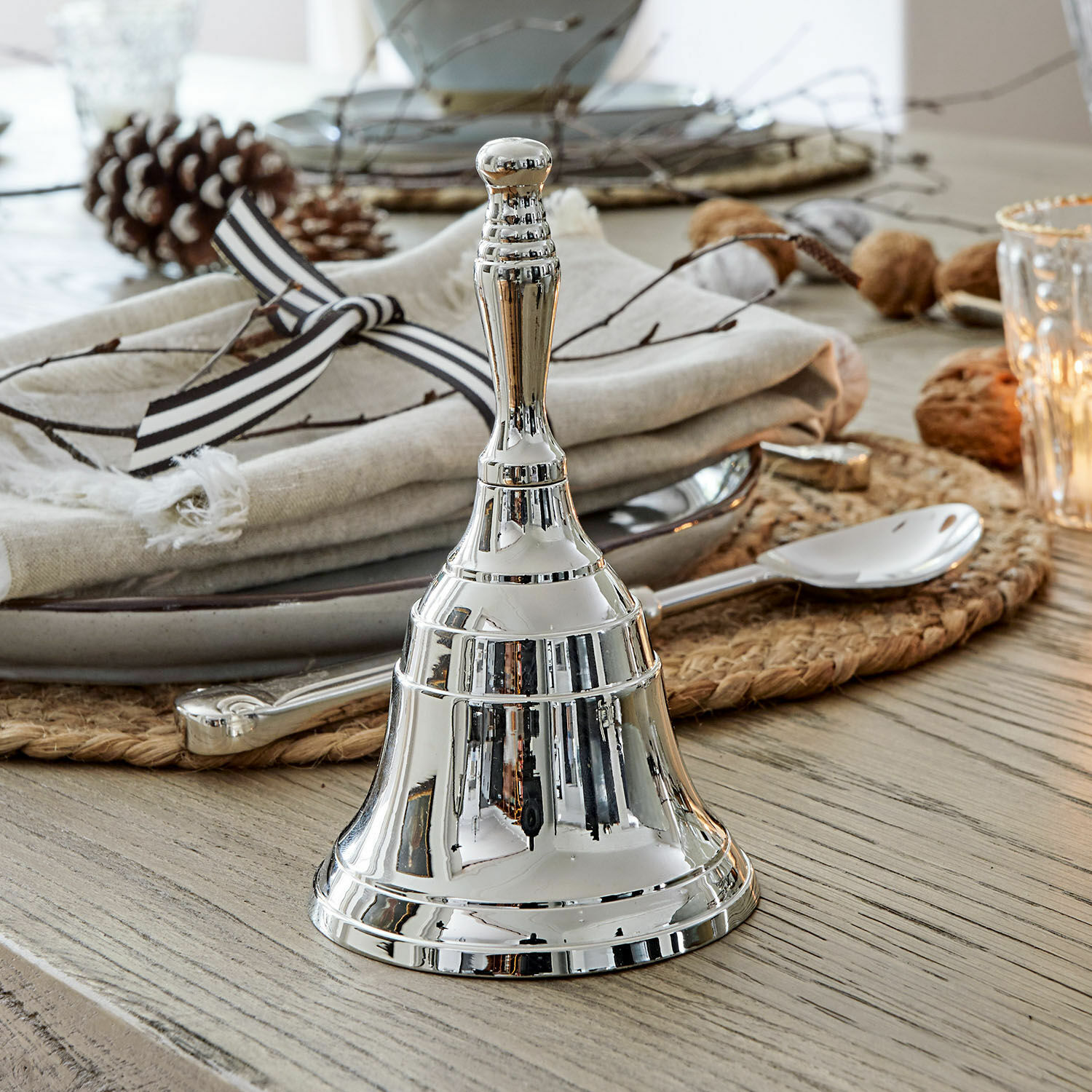 Glocke Baron Silberne Metall-Tischglocke auf Holztisch mit Dekoration und Besteck