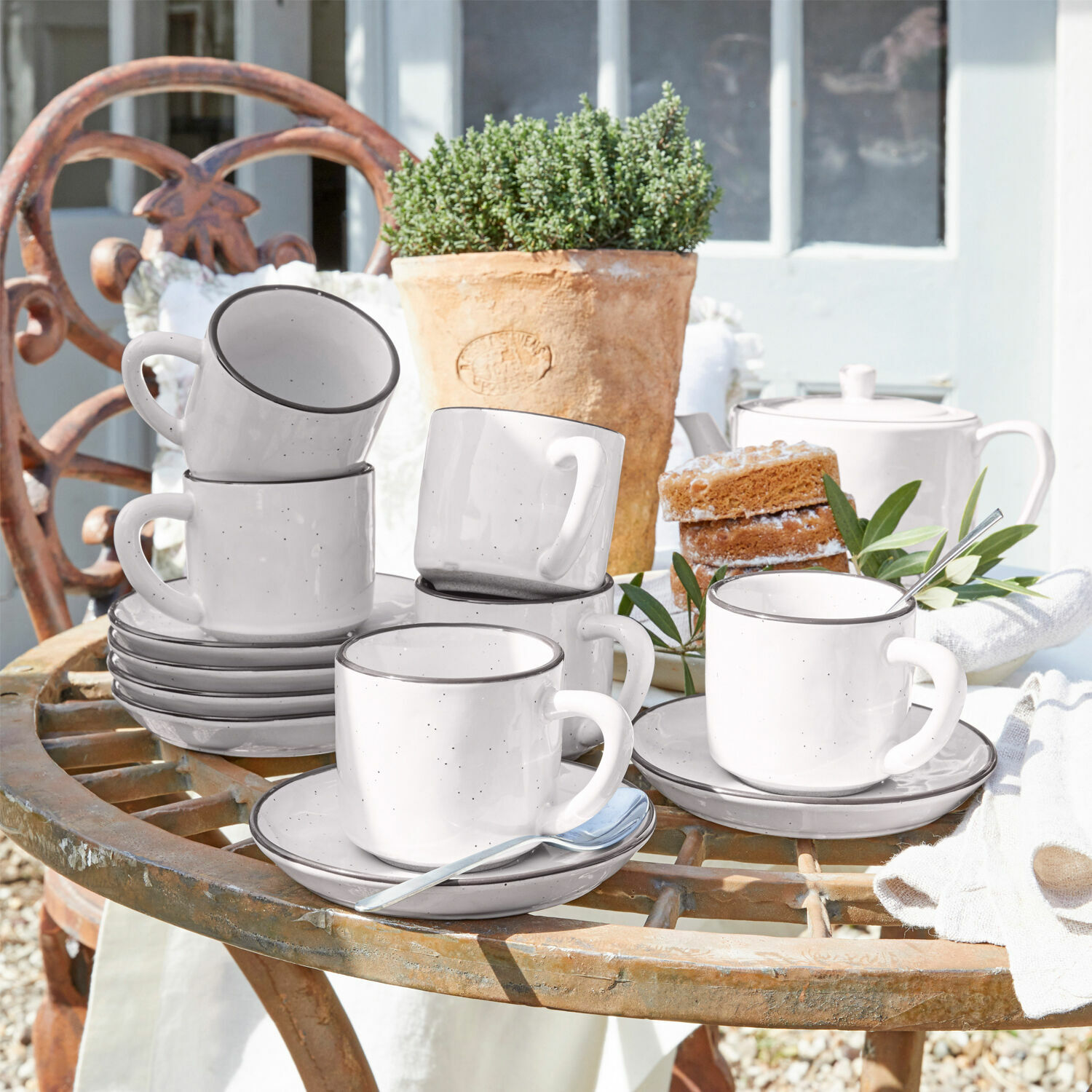 Tasse mit Untertasse 6er Set Biarré Set aus weissen Keramiktassen mit Untertassen auf rustikalem Gartentisch mit Kuchen und Blumentopf
