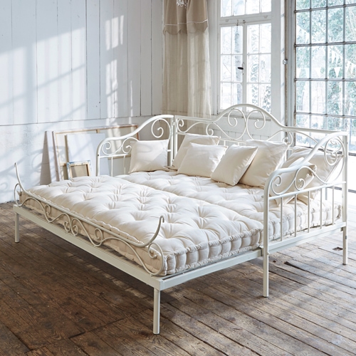 Weisse Metallsofa mit cremefarbenem Matratze und Kissen in hellem Raum mit Holzboden