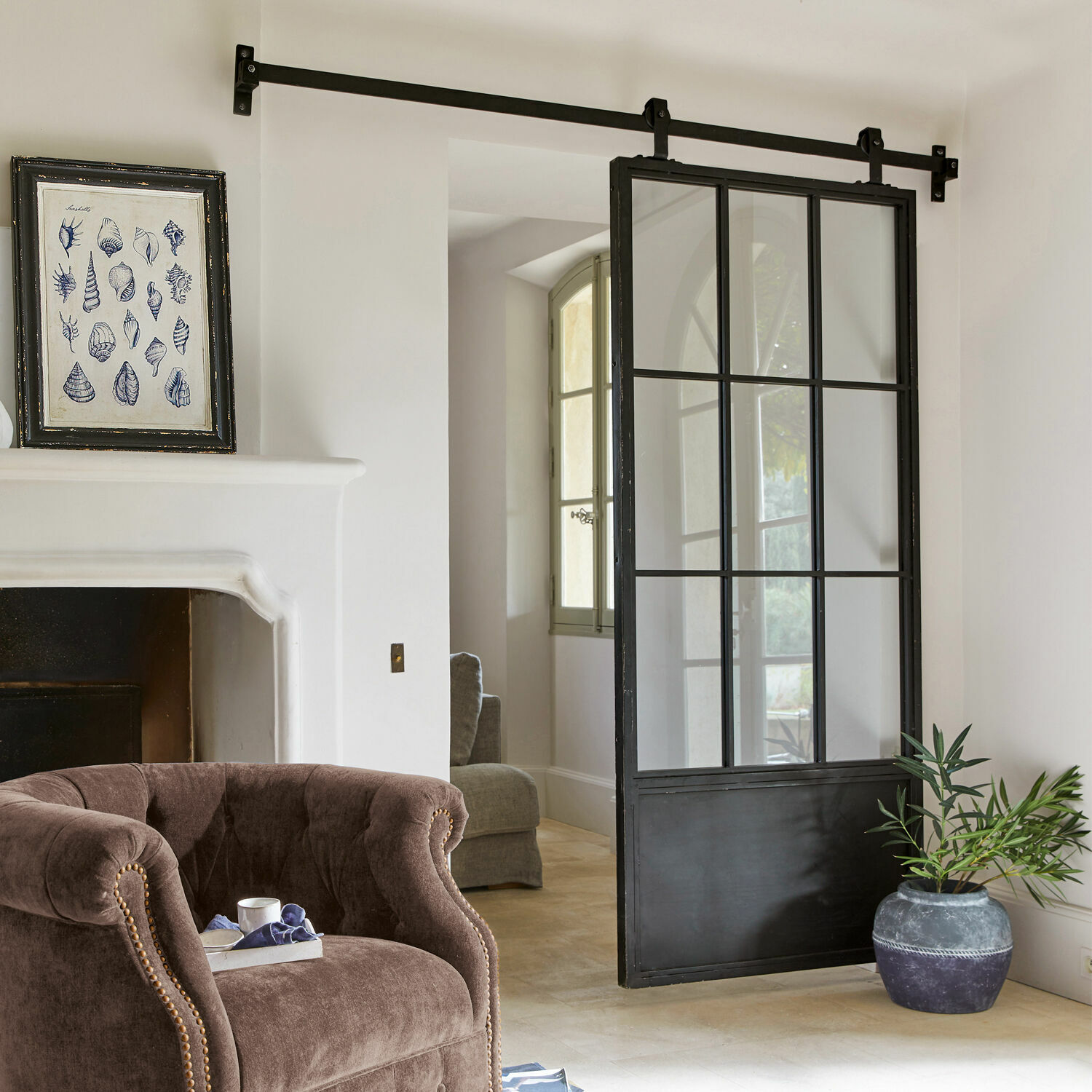 Schiebetür Luisant Schiebetür im Loft-Stil aus schwarzem Metall und Glas in modernem Raum mit Sessel und Cheminée