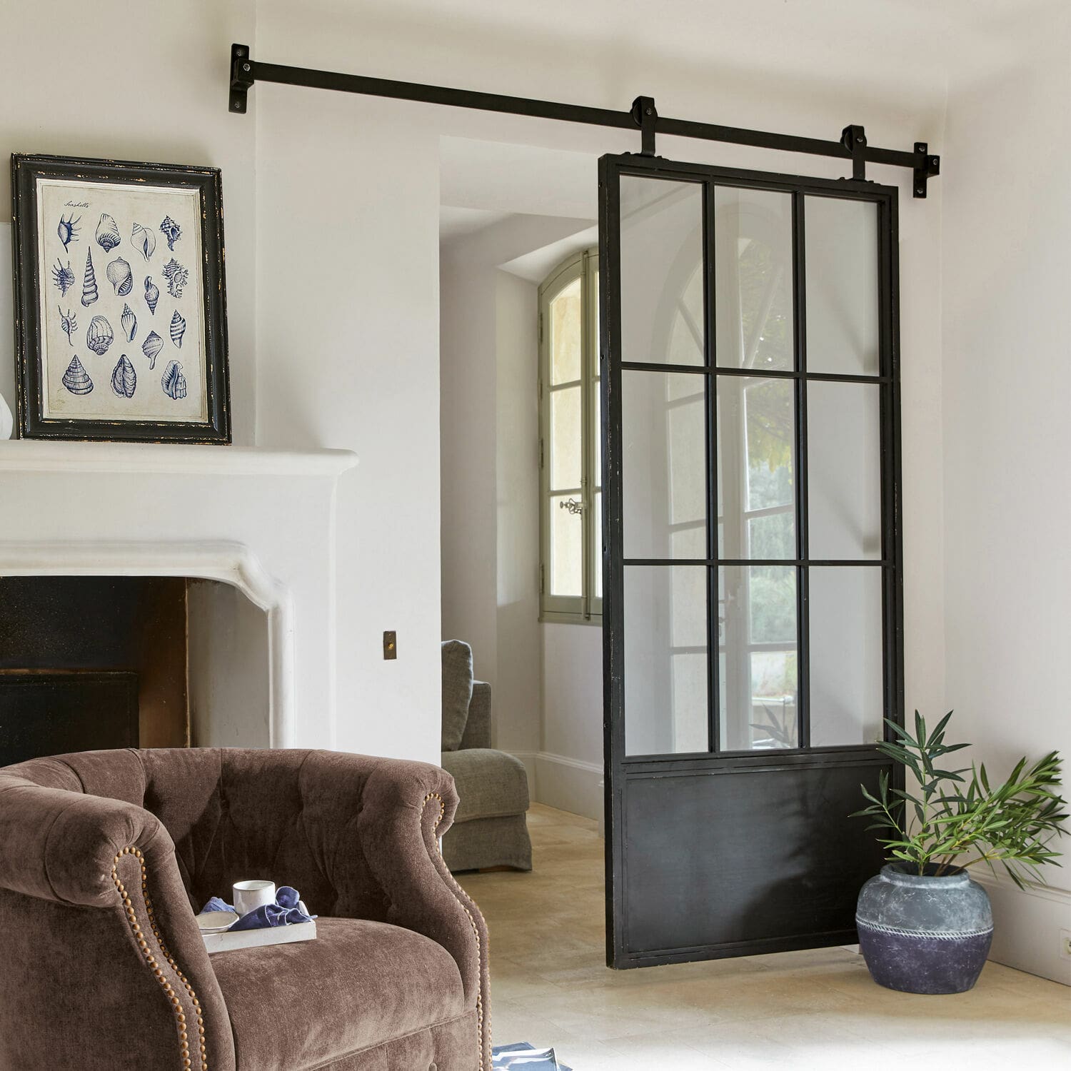 Schiebetür Luisant Schiebetür im Loft-Stil aus schwarzem Metall und Glas in modernem Raum mit Sessel und Cheminée