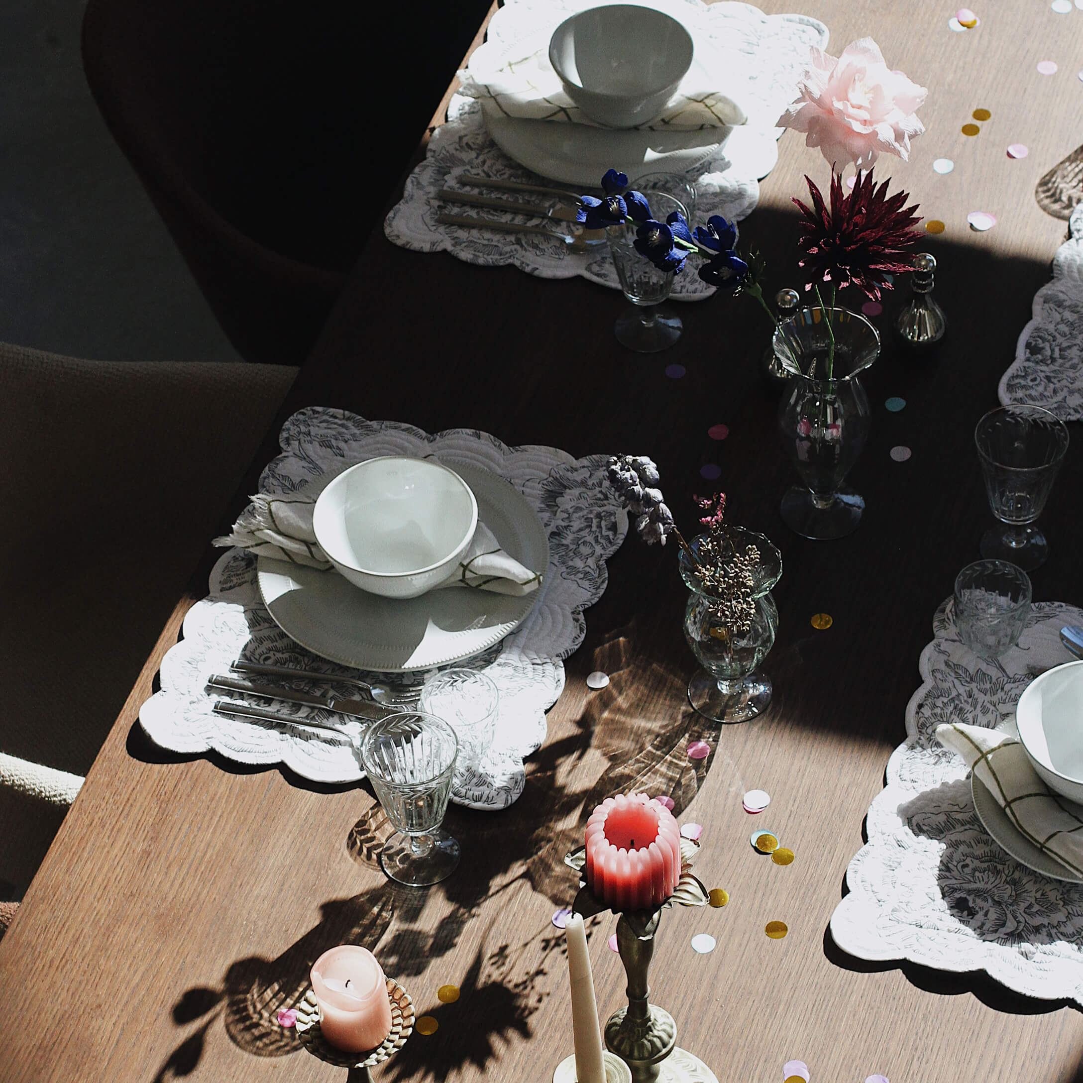 Eleganter gedeckter Tisch mit weissem Porzellan, Gläsern und Kerzen auf Holzplatte