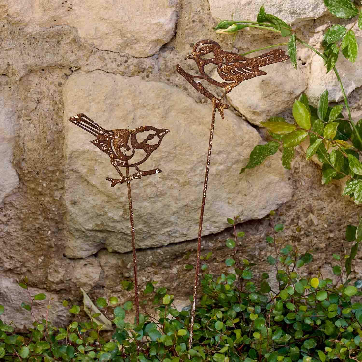 Dekorative rostige Metallvögel auf Stäben als Gartendekoration für Pflanzen und Beete