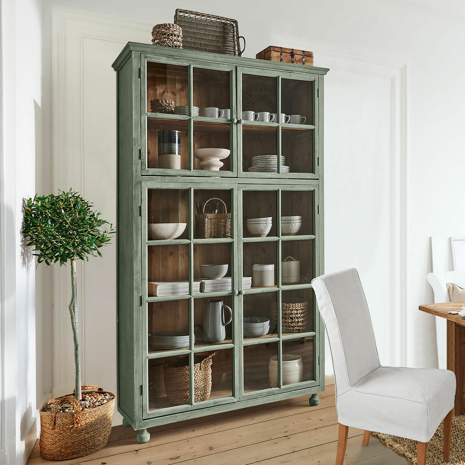 Schrank Bellac Grüner Holzvitrinenschrank mit Glastüren und rustikaler Dekoration im Wohnzimmer