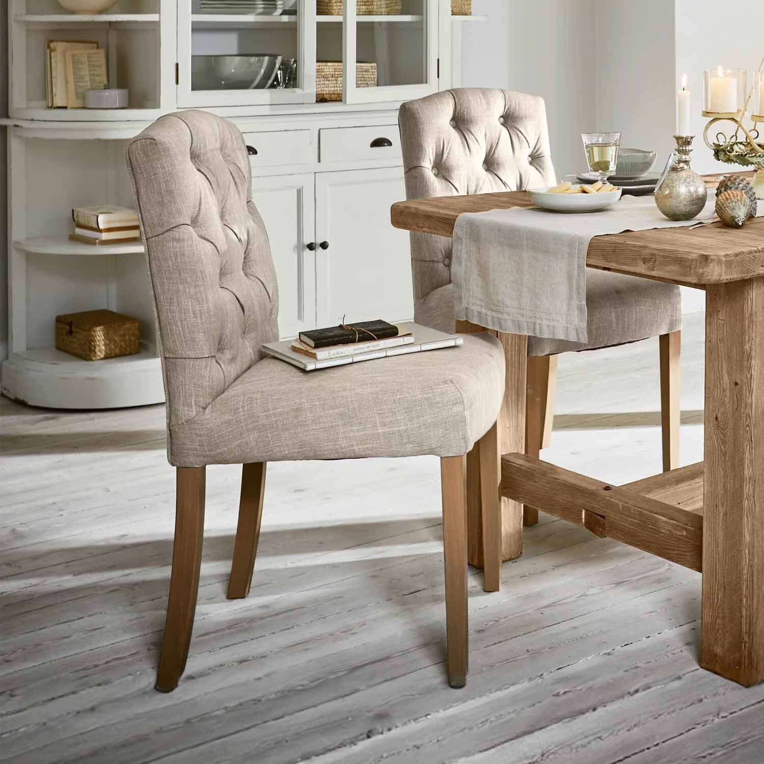 Beiger gepolsterter Stuhl mit Holzbeinen an Holztisch in hellem Esszimmer