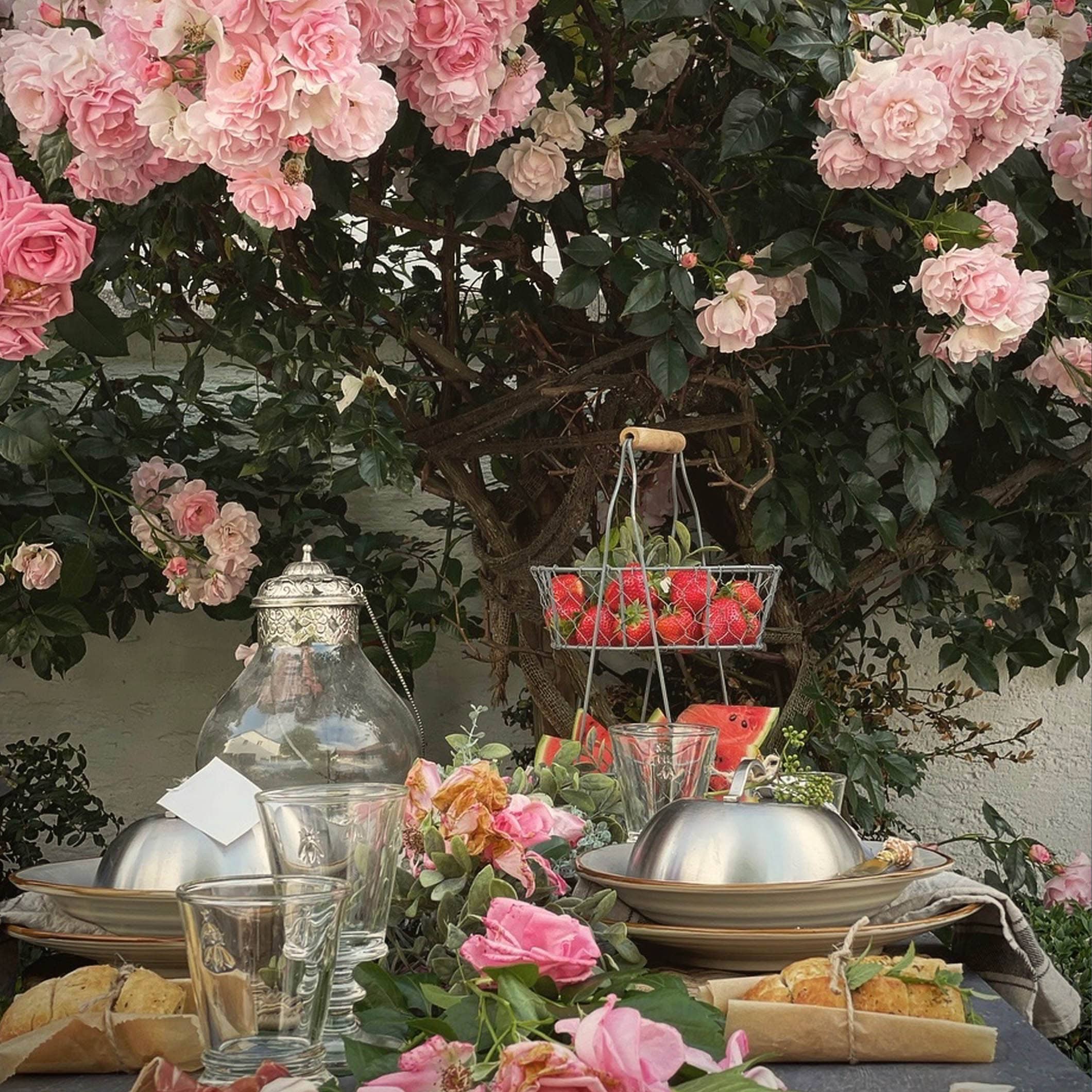 Gartentisch mit Rosen-Dekoration und frischen Früchten, ideal für sommerliche Mahlzeiten im Freien