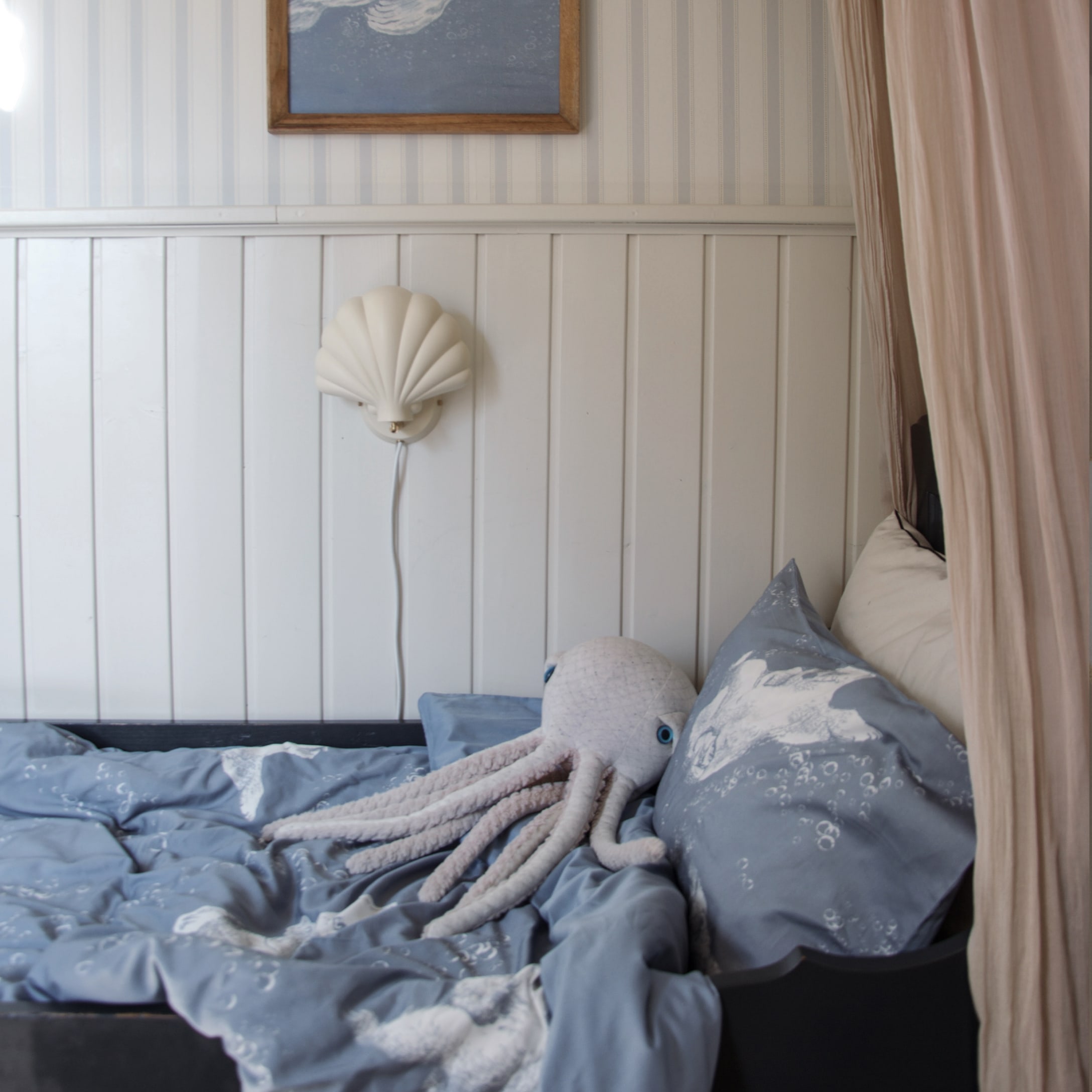 Blaue Kinderbettwäsche mit Oktopus-Motiv und Plüschoktopus auf einem Bett im Kinderzimmer