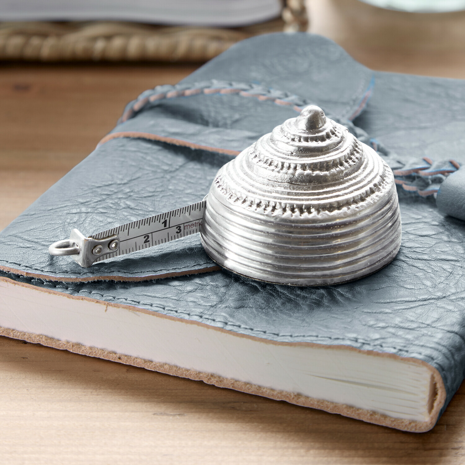 Silbernes Metall-Massband in Muschelform auf blauem Leder-Notizbuch