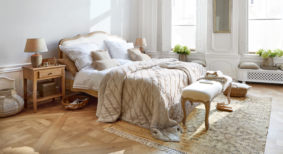 Gemütliches Schlafzimmer im French Chic mit Holzbett und beiger Bettwäsche aus Naturmaterialien