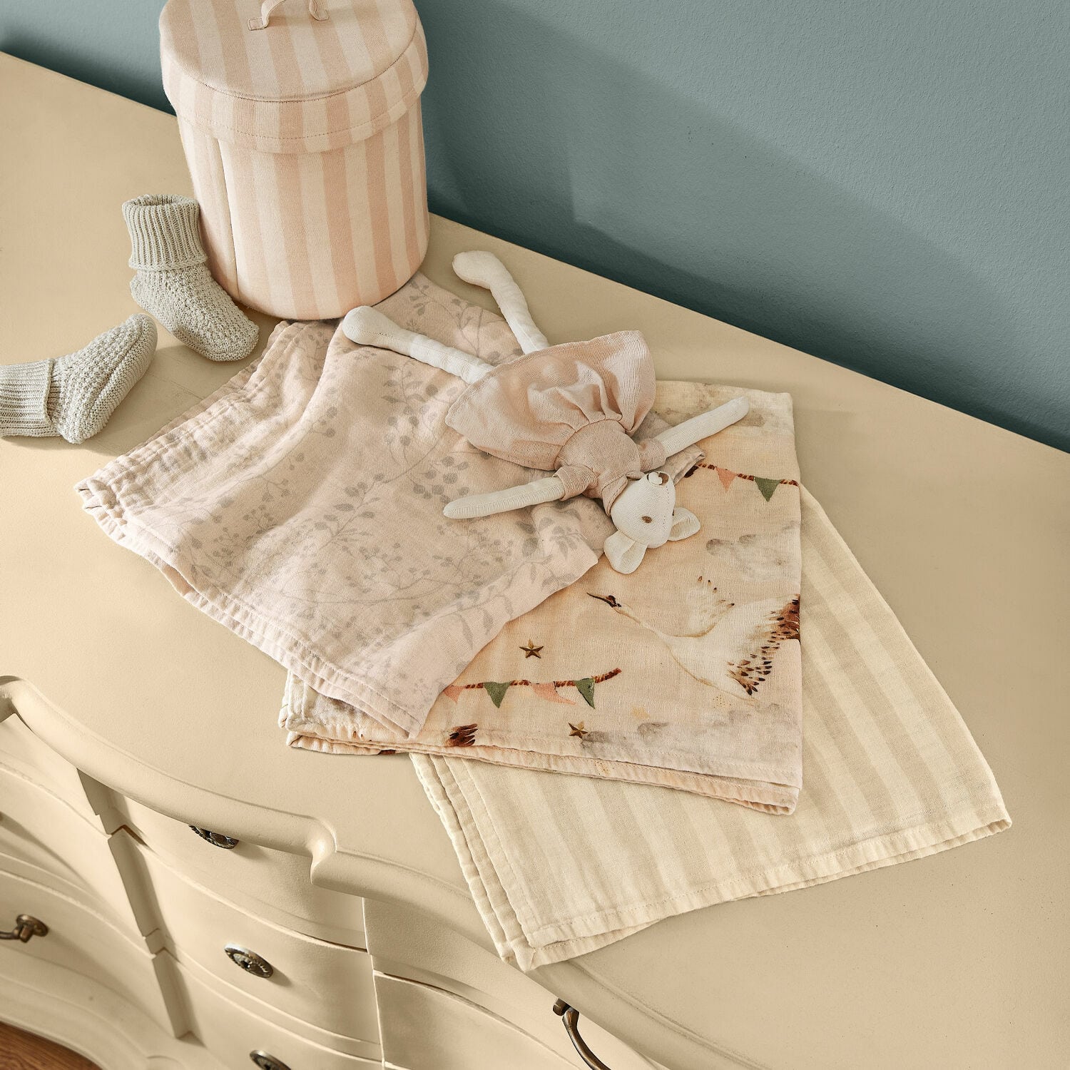 Babytuch 3er Set Bellise Zarte Baumwollwindeln und ein Plüschtier in Pastellfarben auf einer cremefarbenen Kommode