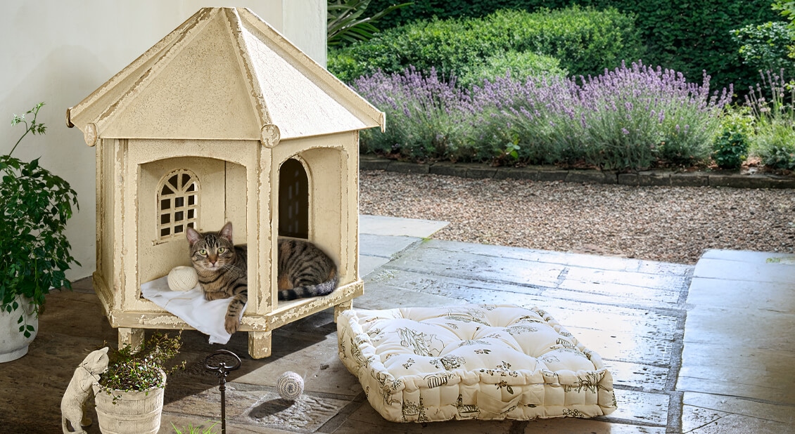 Beiger Katzenpavillon aus Holz mit Kissen und Katze im Garten, gemütlicher Rückzugsort für Haustiere