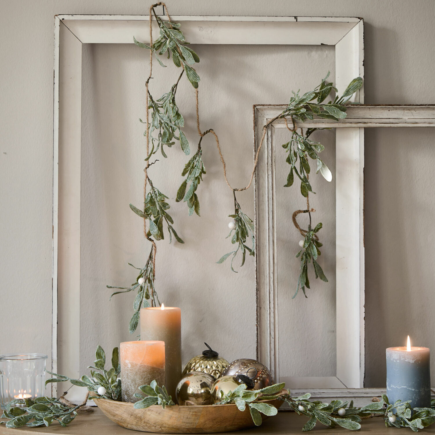 Girlande Mistletoe Dekorative Girlande mit grünen Blättern und weissen Beeren vor weissem Holzrahmen, Kerzen und Dekoration