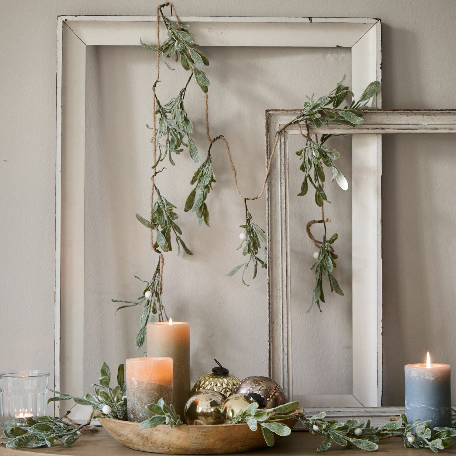 Girlande Mistletoe Dekorative Girlande mit grünen Blättern und weissen Beeren vor weissem Holzrahmen, Kerzen und Dekoration